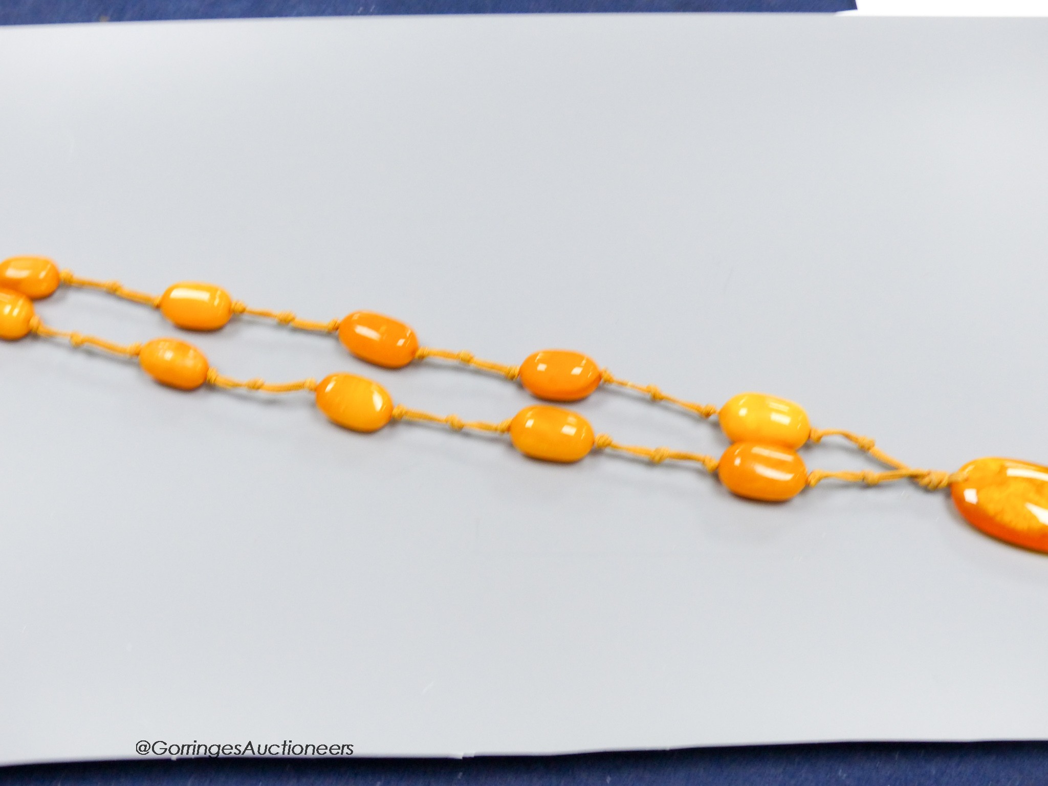 A single strand oval amber bead pendant necklace, 92cm, gross weight 60 grams.